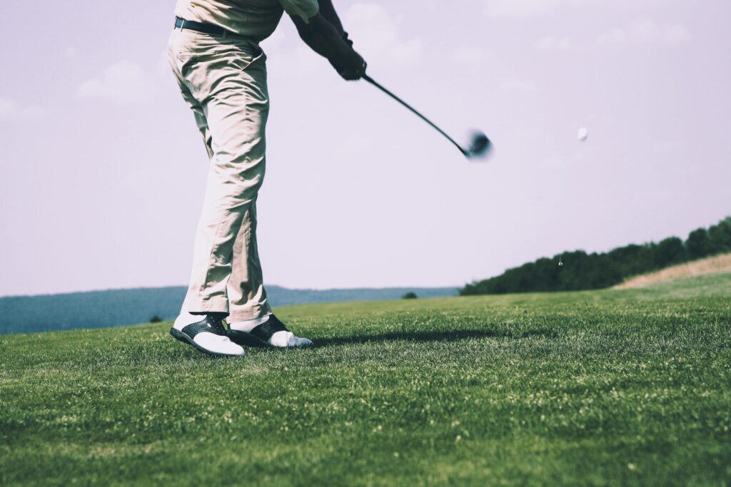 Home 5 A golfer in mid-swing on a sunny day at the golf course, showing motion and focus.